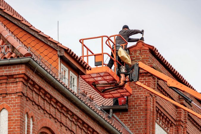 Takläggare under arbete på ett tegeltak. Lutning, tillgänglighet och underlagets skick avgör tillsammans en stor del av den totala kostnaden.